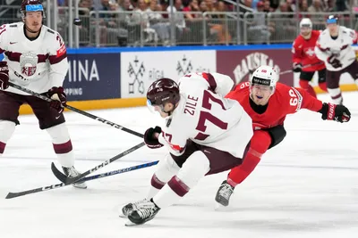Kristaps Zile of Latvia, front, fights for a puck with Fabrice Herzog of Switzerland during the group B match between Latvia and Switzerland at the ice hockey world championship in Riga, Latvia, Tuesday, May 23, 2023. (AP Photo/Roman Koksarov)