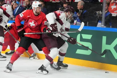 Oskars Batna of Latvia, right, fights for a puck with Tanner Richard of Switzerland during the group B match between Latvia and Switzerland at the ice hockey world championship in Riga, Latvia, Tuesday, May 23, 2023. (AP Photo/Roman Koksarov)
