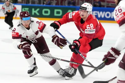 Karlis Cukste of Latvia, left, fights for a puck with Fabrice Herzog of Switzerland during the group B match between Latvia and Switzerland at the ice hockey world championship in Riga, Latvia, Tuesday, May 23, 2023. (AP Photo/Roman Koksarov)