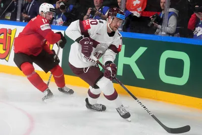 Miks Indrasis of Latvia, right, fights for a puck with Sven Senteler of Switzerland during the group B match between Latvia and Switzerland at the ice hockey world championship in Riga, Latvia, Tuesday, May 23, 2023. (AP Photo/Roman Koksarov)