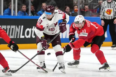 Rihards Bukarts of Latvia, left, fights for a puck with Sven Senteler of Switzerland during the group B match between Latvia and Switzerland at the ice hockey world championship in Riga, Latvia, Tuesday, May 23, 2023. (AP Photo/Roman Koksarov)