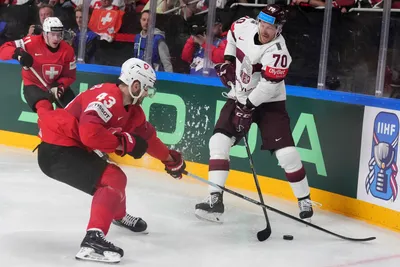 Miks Indrasis of Latvia, right, fights for a puck with Andrea Glauser of Switzerland during the group B match between Latvia and Switzerland at the ice hockey world championship in Riga, Latvia, Tuesday, May 23, 2023. (AP Photo/Roman Koksarov)