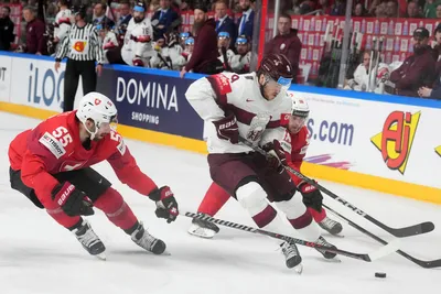 Renars Krastenbergs of Latvia, right, fights for a puck with Romain Loeffel of Switzerland during the group B match between Latvia and Switzerland at the ice hockey world championship in Riga, Latvia, Tuesday, May 23, 2023. (AP Photo/Roman Koksarov)