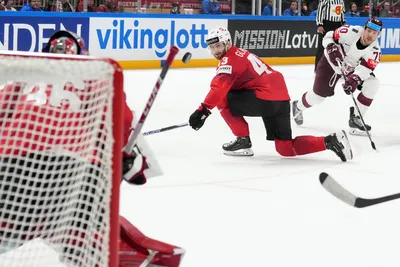 Miks Indrasis of Latvia, right, fights for a puck with Andrea Glauser, center, and goalie Joren Pottelberghe of Switzerland during the group B match between Latvia and Switzerland at the ice hockey world championship in Riga, Latvia, Tuesday, May 23, 2023. (AP Photo/Roman Koksarov)
