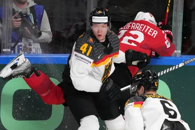 Jonas Muller of Germany, left, fights for a puck with Nino Niederreiter of Switzerland during the quarter final match between Germany and Switzerland at the ice hockey world championship in Riga, Latvia, Thursday, May 25, 2023. (AP Photo/Roman Koksarov)