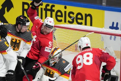 Jonas Muller of Germany, left, and goalie Mathias Niederberger, centre right, fight for a puck with Marco Miranda, right, and Gaetan Haas of Switzerland during the quarter final match between Germany and Switzerland at the ice hockey world championship in Riga, Latvia, Thursday, May 25, 2023. (AP Photo/Roman Koksarov)