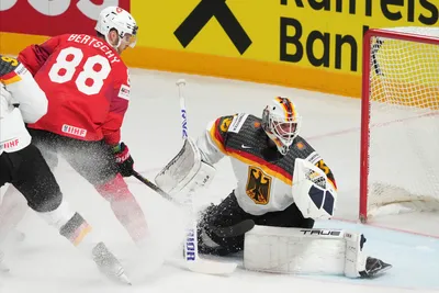 Goalie Mathias Niederberger of Germany, right, fights for a puck with Christoph Bertschy of Switzerland during the quarter final match between Germany and Switzerland at the ice hockey world championship in Riga, Latvia, Thursday, May 25, 2023. (AP Photo/Roman Koksarov)