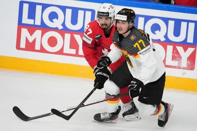 Daniel Fischbuch of Germany, right, fights for a puck with Jonas Siegenthalerof Switzerland during the quarter final match between Germany and Switzerland at the ice hockey world championship in Riga, Latvia, Thursday, May 25, 2023. (AP Photo/Roman Koksarov)