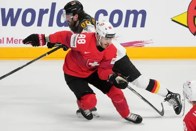 Wojciech Stachowiak of Germany, back, fights for a puck with Christoph Bertschy of Switzerland during the quarter final match between Germany and Switzerland at the ice hockey world championship in Riga, Latvia, Thursday, May 25, 2023. (AP Photo/Roman Koksarov)