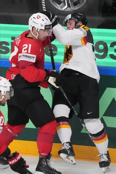 Justin Schutz of Germany, right, fights for a puck with Kevin Fiala of Switzerland during the quarter final match between Germany and Switzerland at the ice hockey world championship in Riga, Latvia, Thursday, May 25, 2023. (AP Photo/Roman Koksarov)