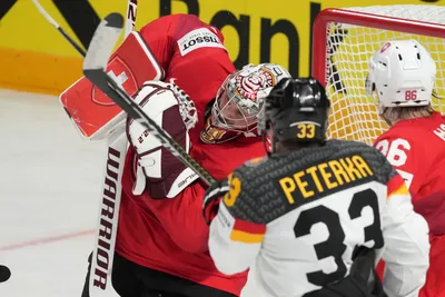 John Peterka of Germany, right, fights for a puck with goalieRobert Mayer of Switzerland during the quarterfinal match between Germany and Switzerland at the ice hockey world championship in Riga, Latvia, Thursday, May 25, 2023. (AP Photo/Roman Koksarov)
