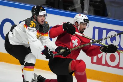John Peterka of Germany, left, fights for a puck with Jonas Siegenthaler of Switzerland during the quarterfinal match between Germany and Switzerland at the ice hockey world championship in Riga, Latvia, Thursday, May 25, 2023. (AP Photo/Roman Koksarov)