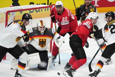 Goalie Mathias Niederberger of Germany, centre, fights for a puck with Nino Niederreiter of Switzerland during the quarterfinal match between Germany and Switzerland at the ice hockey world championship in Riga, Latvia, Thursday, May 25, 2023. (AP Photo/Roman Koksarov)
