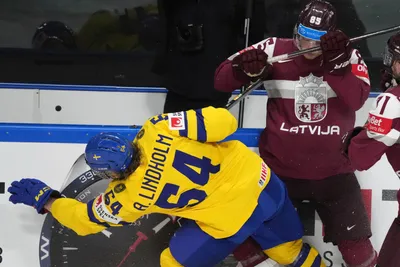 Dans Locmelis of Latvia, right, fights for a puck with Anton Lindholm of Sweden during the quarter final match between Latvia and Sweden at the ice hockey world championship in Riga, Latvia, Thursday, May 25, 2023. (AP Photo/Roman Koksarov)
