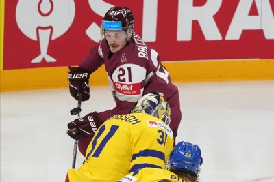 Rudolfs Balcers of Latvia, back, fights for a puck with goalie Lars Johansson of Sweden during the quarter final match between Latvia and Sweden at the ice hockey world championship in Riga, Latvia, Thursday, May 25, 2023. (AP Photo/Roman Koksarov)