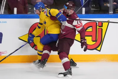 Miks Indrasis of Latvia, right, fights for a puck with Anton Lindholm of Sweden during the quarter final match between Latvia and Sweden at the ice hockey world championship in Riga, Latvia, Thursday, May 25, 2023. (AP Photo/Roman Koksarov)