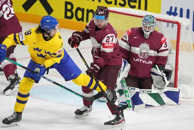 Goalie Arturs Silovs, ruight, Oskars Cibulskis, centre, of Latvia, fight for a puck with Dennis Everberg of Sweden during the quarter final match between Latvia and Sweden at the ice hockey world championship in Riga, Latvia, Thursday, May 25, 2023. (AP Photo/Roman Koksarov)