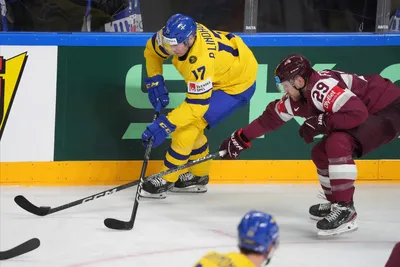 Ralfs Freibergs of Latvia, right, fights for a puck with Par Lindholm of Sweden during the quarter final match between Latvia and Sweden at the ice hockey world championship in Riga, Latvia, Thursday, May 25, 2023. (AP Photo/Roman Koksarov)
