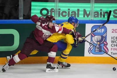 Rihards Bukarts of Latvia, left, fights for a puck with Patrik Nemeth of Sweden during the quarter final match between Latvia and Sweden at the ice hockey world championship in Riga, Latvia, Thursday, May 25, 2023. (AP Photo/Roman Koksarov)