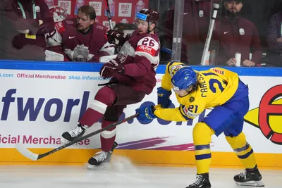 Uvis Balinskis of Latvia, left, fights for a puck with Leo Carlsson of Sweden during the quarter final match between Latvia and Sweden at the ice hockey world championship in Riga, Latvia, Thursday, May 25, 2023. (AP Photo/Roman Koksarov)