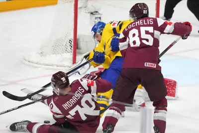Dans Locmelis, right, and Miks Indrasis, bottom, of Latvia, fight for a puck with goalie Lars Johansson of Sweden during the quarter final match between Latvia and Sweden at the ice hockey world championship in Riga, Latvia, Thursday, May 25, 2023. (AP Photo/Roman Koksarov)