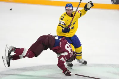 Oskars Batna of Latvia, left, fights for a puck with Patrik Nemeth of Sweden during the quarter final match between Latvia and Sweden at the ice hockey world championship in Riga, Latvia, Thursday, May 25, 2023. (AP Photo/Roman Koksarov)