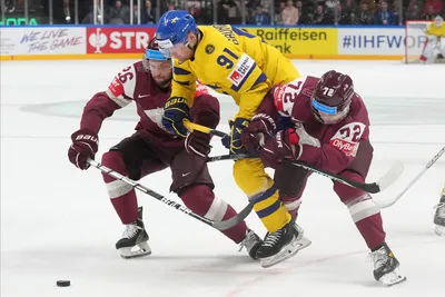 Janis Jaks, right, and Uvis Balinskis, left, of Latvia, fight for a puck with Carl Grundstrom of Sweden during the quarter final match between Latvia and Sweden at the ice hockey world championship in Riga, Latvia, Thursday, May 25, 2023. (AP Photo/Roman Koksarov)