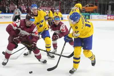 Oskars Cibulskis of Latvia, left, fights for a puck with Par Lindholm of Sweden during the quarter final match between Latvia and Sweden at the ice hockey world championship in Riga, Latvia, Thursday, May 25, 2023. (AP Photo/Roman Koksarov)