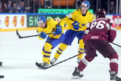 Jonathan Pudas of Sweden, left, makes a shot during the quater final match between Latvia and Sweden at the ice hockey world championship in Riga, Latvia, Thursday, May 25, 2023. (AP Photo/Roman Koksarov)