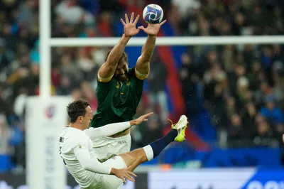 England's Alex Mitchell, left kicks the ball clear as South Africa's Eben Etzebeth attempts the charge down during the Rugby World Cup semifinal match between England and South Africa at the Stade de France in Saint-Denis, outside Paris, Saturday, Oct, 21, 2023. (AP Photo/Christophe Ena)