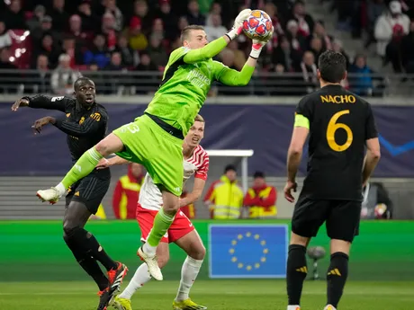 Brankár Andrij Lunin (hore) chytá loptu pred Danim Olmom v zápase osemfinále Ligy majstrov RB Lipsko - Real Madrid
