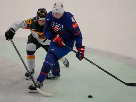 Luke Hughes a Parker Tuomie v súboji o puk v zápase USA - Nemecko na MS v hokeji 2024.