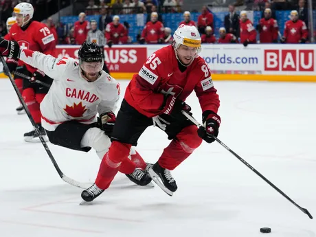 Jamie Oleksiak a Sven Andrighetto v súboji o puk v zápase Kanada - Švajčiarsko v semifinále MS v hokeji 2024.