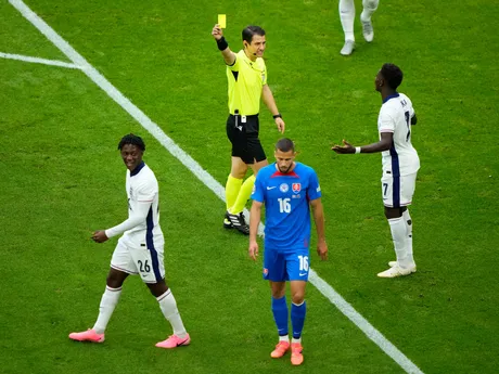 Kobbie Mainoo po obdržaní žltej karty a Bukayo Saka v rozhovore s rozhodcom v zápase Slovensko - Anglicko v osemfinále EURO 2024.