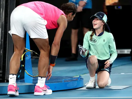 Rafael Nadal podáva čelenku zberačke loptičiek, ktorú trafil loptičkou počas zápasu 2. kola dvojhry proti Argentínčanovi Federicovi Delbonisovi na grandslamovom turnaji Australian Open.