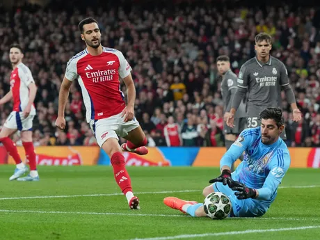 Na snímke brankár Realu Madrid Thibaut Courtois chytá loptu pred Mikelom Merinom z Arsenalu počas štvrťfinálového zápasu Ligy majstrov FC Arsenal - Real Madrid.