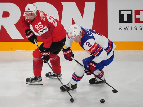 Švajčiarsky hráč Sven Andrighetto (vľavo) bojuje o puk s Američanom Jacksonom Lacombem vo finále Švajčiarsko - USA na MS 2025 v hokeji.