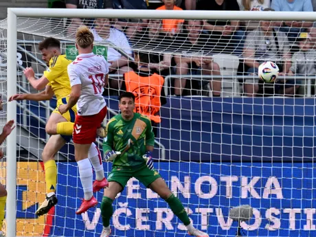 Hlavičkujúci Conrad Harder a brankár Ruslan Neshcheret v zápase Ukrajina - Dánsko v skupine D na EURO U21 2025.