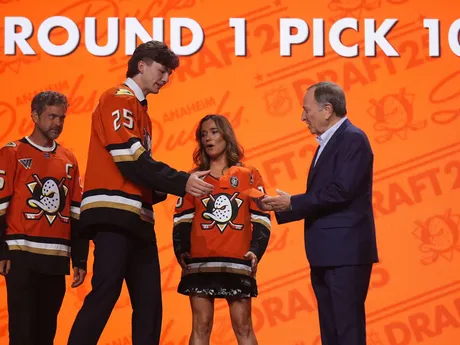 Roger McQueen (druhý zľava) prijíma čiapku od komisára NHL Garyho Bettmana (vpravo) po tom, ako si ho v piatkovom drafte NHL 27. júna 2025 v Los Angeles vybral tím Anaheim Ducks.