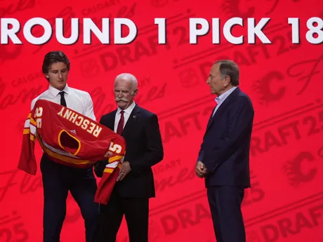 Cole Reschny (vľavo) si oblieka dres vedľa Lannyho McDonalda (uprostred) a komisára NHL Garyho Bettmana po tom, ako si ho v piatkovom drafte NHL 27. júna 2025 v Los Angeles vybral tím Calgary Flames.