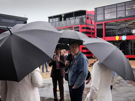 Návštevníci sa ukrývajú pod dáždnikmi počas dažďa na pretekárskom okruhu Silverstone pred Veľkou cenou Veľkej Británie.