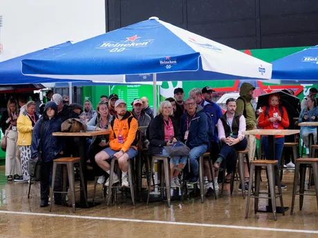 Návštevníci sa ukrývajú pod dáždnikmi počas dažďa na pretekárskom okruhu Silverstone pred Veľkou cenou Veľkej Británie.