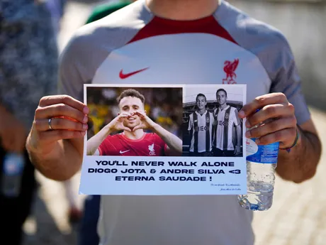 Fanúšik drží transparent s fotografiami pred kostolom, kam priviezli telá útočníka Liverpoolu Dioga Jotu a Andrého Silvu