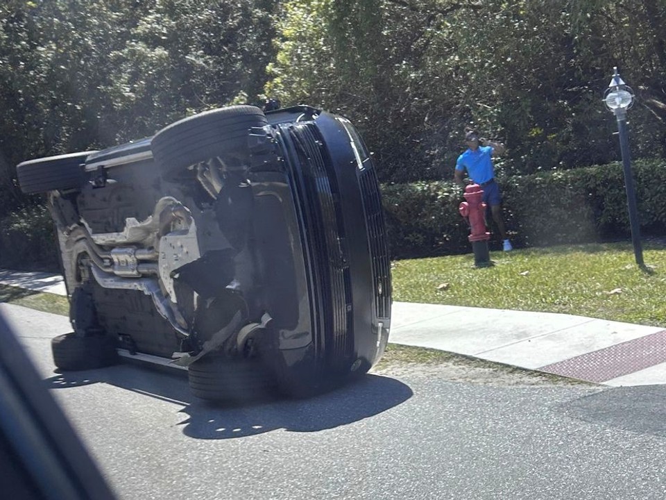 Golfista Tiger Woods stojí pri svojom prevrátenom vozidle.