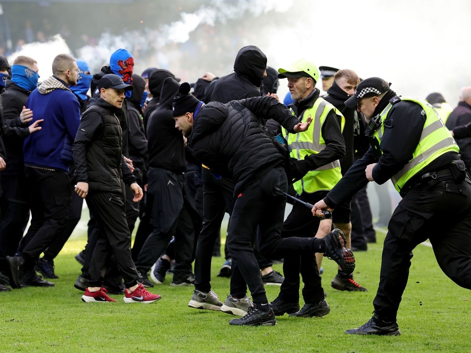 Usporiadatelia a policajti zasahujú počas bitky fanúšikov, ktorá sa strhla na ihrisku po penaltovom rozstrele po štvrťfinále Škótskeho pohára Rangers FC - Celtic Glasgow.