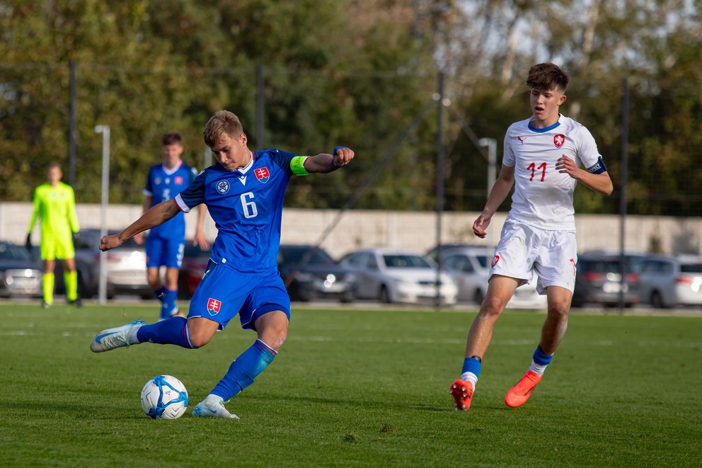 V nominácii slovenskej šestnástky figuruje aj Jakub Koščo. Na sníme v modrom strieľa cez Matouša Srba v prípravnom zápase Slovensko U16 – Česko U16 v Dunajskej Strede (1.10.2024)