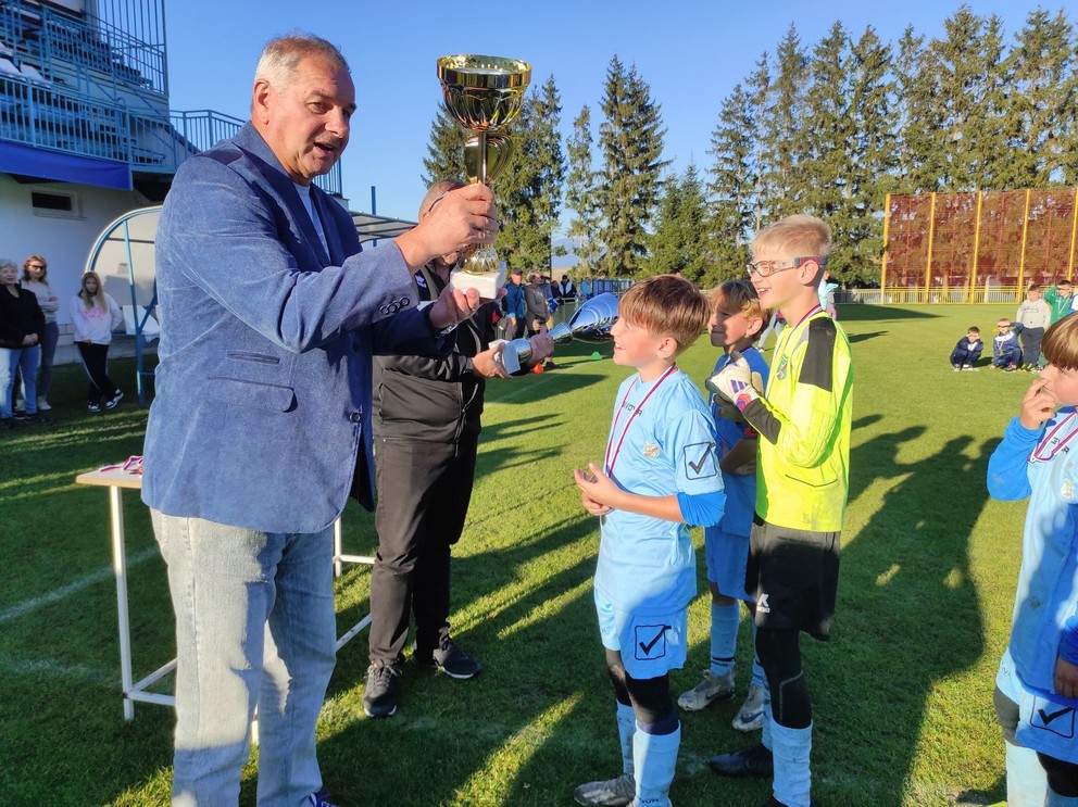 Predseda SsFZ Stanislav Neuschl odovzdáva pohár víťaznému výberu Oravského futbalového zväzu.