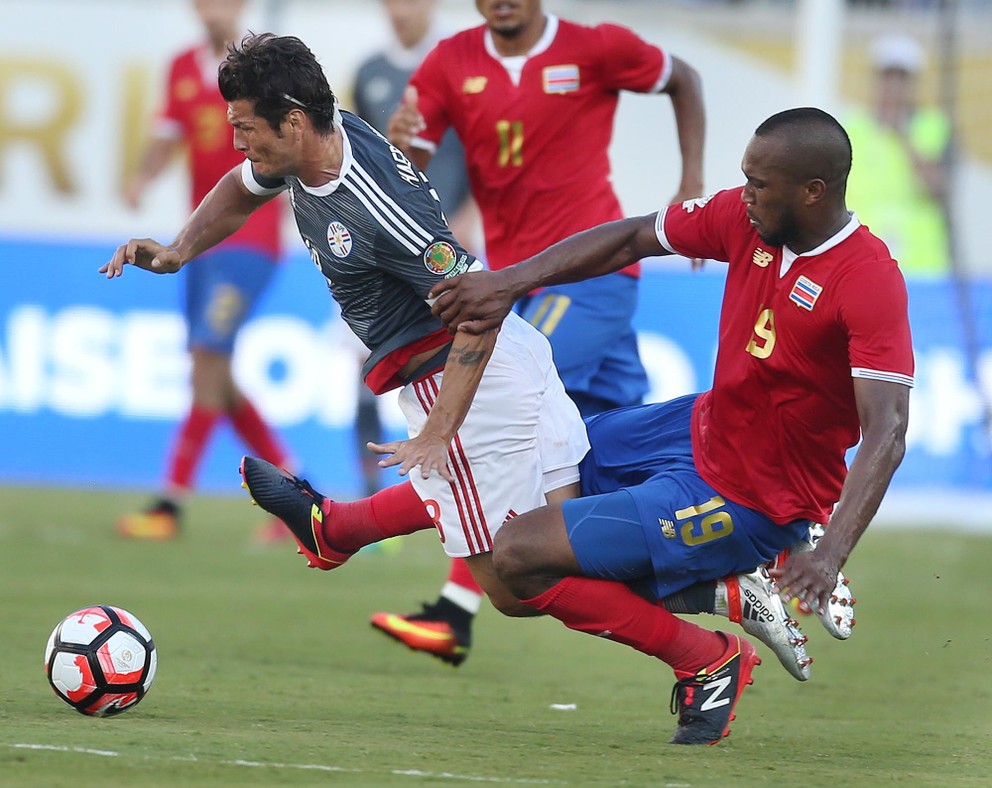 Kostarický obranca (vpravo) videl v nadstavenom čase červenú kartu za tento zákrok.