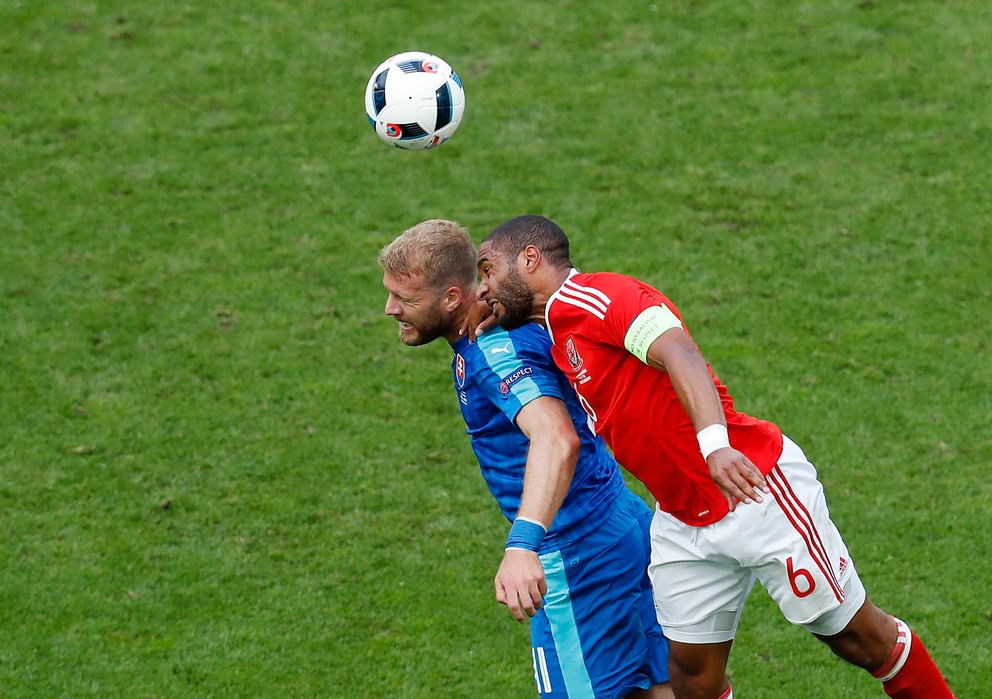 Adam Nemec (vľavo) bojuje v hlavičkovom súboji o loptu s kapitánom Walesu Ashleym Williamsom.