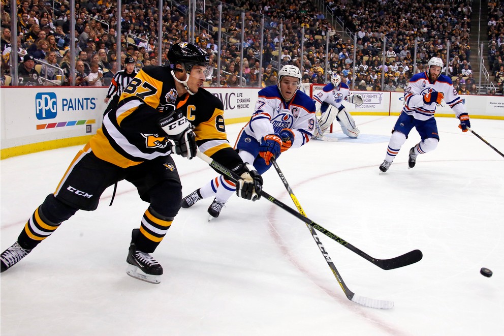 Sidney Crosby (vľavo) rozohráva puk v zápase proti Edmontonu.